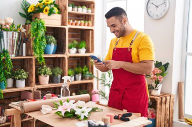 Young hispanic man florist make photo to flower by smartphone at florist