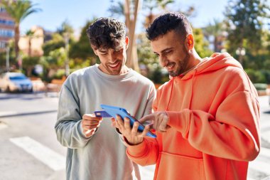 Caddede dokunmatik ped ve kredi kartı kullanan iki erkek.