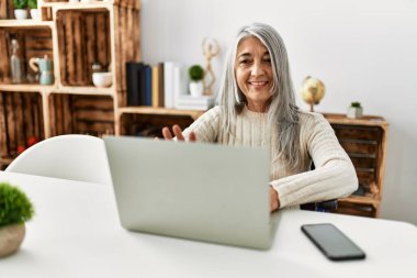 Orta yaşlı, kır saçlı, gülümseyen bir kadın.