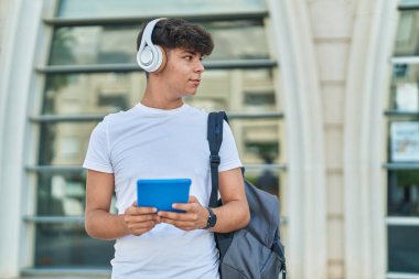 Latin kökenli genç bir öğrenci üniversitede müzik dinlerken touchpad kullanıyor.