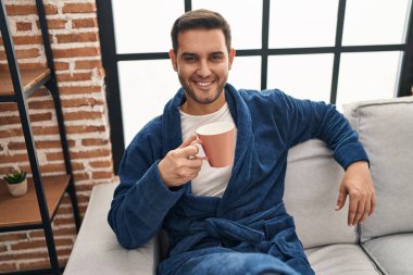 Evde kahve içen bornoz giyen genç bir İspanyol.