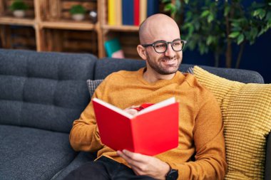 Genç adam kitap okuyor ve evde kahve içiyor.