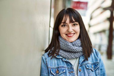 Genç esmer kadın gülümsüyor mutlu duvara yaslanıyor