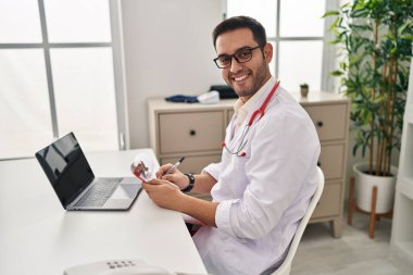 Klinikte çalışan doktor üniforması giyen genç İspanyol adam.