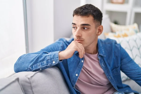 Stock image Young hispanic man sitting on sofa with serious expression at home