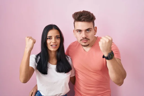 Young Hispanic Couple Standing Pink Background Angry Mad Raising Fist — 图库照片