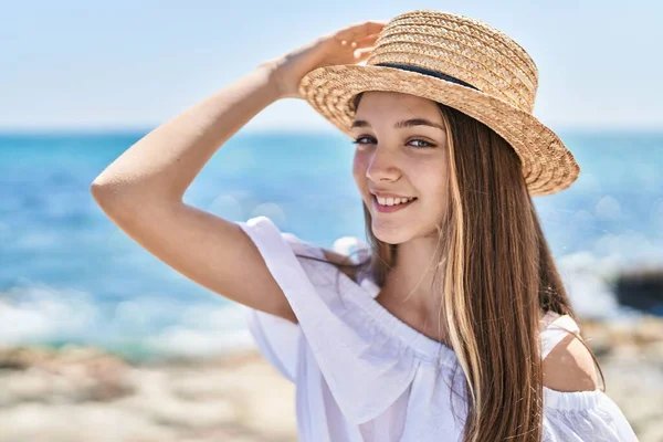 Adorable girl tourist smiling confident wearing summer hat at seaside