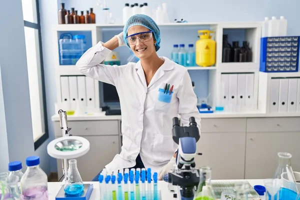 Brunette Woman Working Scientist Laboratory Smiling Confident Touching Hair Hand — Stock Photo, Image