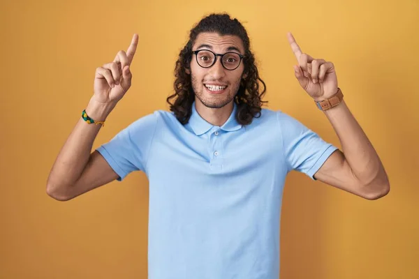 Young Hispanic Man Standing Yellow Background Smiling Amazed Surprised Pointing — Stock Photo, Image