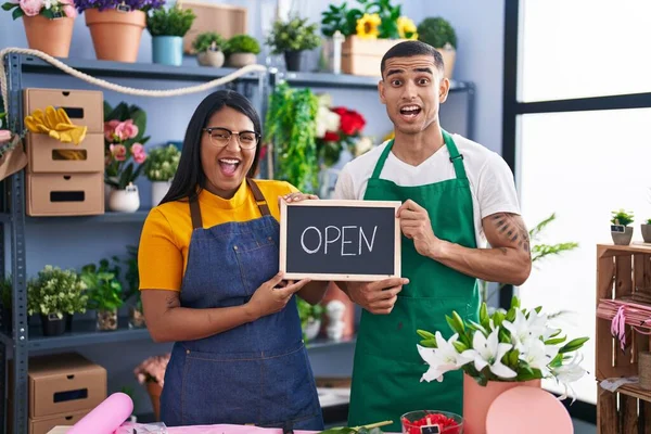Young hispanic couple working at florist with open sign celebrating crazy and amazed for success with open eyes screaming excited.