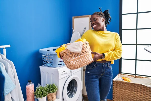 非洲裔美国妇女在洗衣房里拿着装有衣服的篮子闷闷不乐 — 图库照片