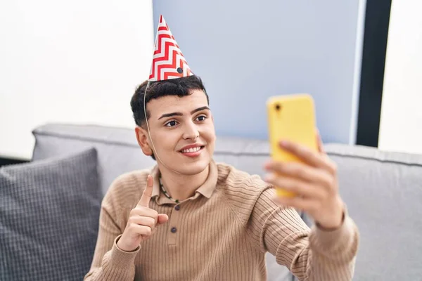 Non binary person celebrating birthday doing video call smiling with an idea or question pointing finger with happy face, number one