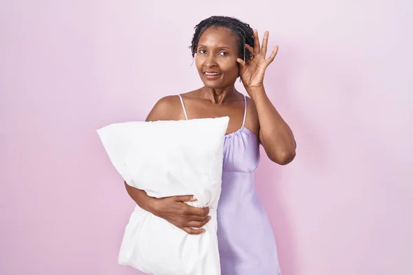 African Woman Dreadlocks Wearing Pajama Hugging Pillow Smiling Hand Ear — Stockfoto