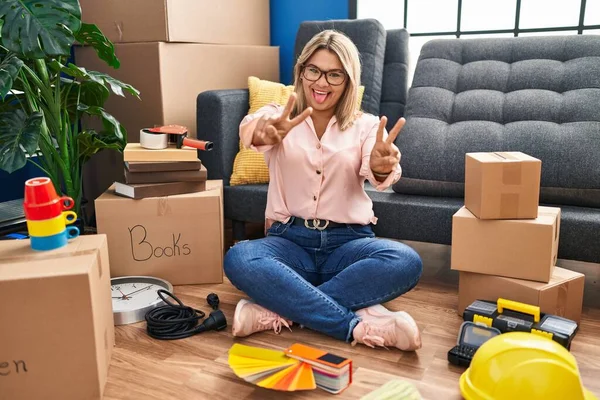 Young Hispanic Woman Moving New Home Sitting Floor Smiling Tongue — Foto de Stock