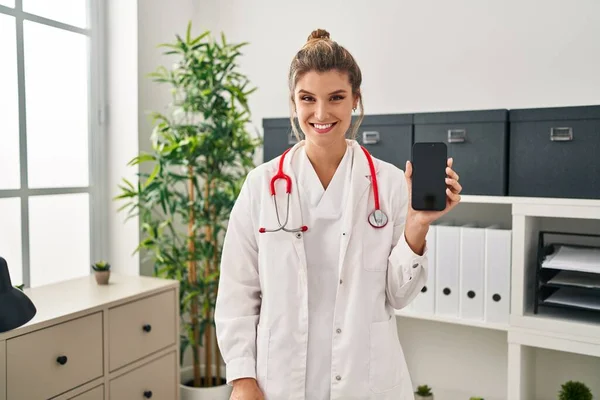 Young Woman Wearing Doctor Uniform Holding Smartphone Looking Positive Happy — Stok fotoğraf