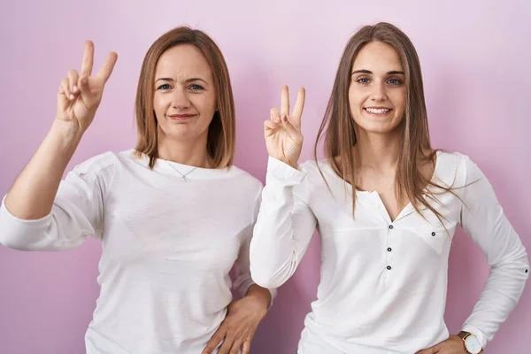Middle Age Mother Young Daughter Standing Pink Background Smiling Looking — ストック写真