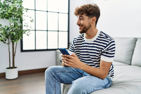 Young arab man smiling confident using smartphone at home