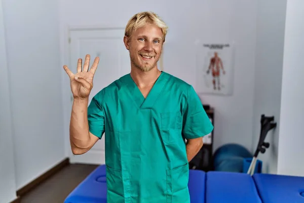 Young Blond Man Wearing Physiotherapist Uniform Standing Clinic Showing Pointing — Stok fotoğraf