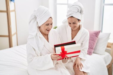 Mother and daughter wearing bathrobe surprise with gift at bedroom
