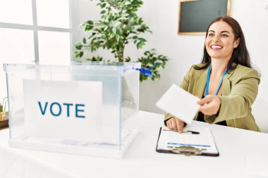 Genç ve güzel İspanyol kadın seçim kurulu başkanı seçim kurulunda oy kağıdı tutuyor.