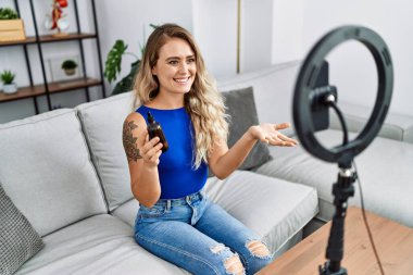 Young woman recording skin care tutorial by smartphone at home