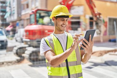Young hispanic man architect using touchpad at park