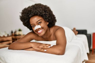 Genç Afrikalı Amerikalı kadın güzellik merkezinde kendine güvenen burun bandı takıyor.