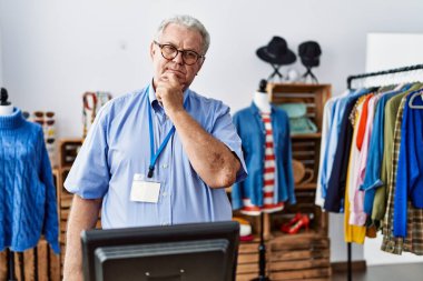 Gri saçlı, perakende mağazasında müdür olarak çalışan son sınıf öğrencisi kameraya kollarını kavuşturup gülümseyen ve çenesini kaldırmış bir şekilde bakıyor. Olumlu düşünmek. 