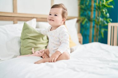 Beyaz bebek yatakta kendinden emin bir şekilde gülümsüyor.