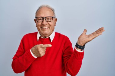 İzole edilmiş arka planda duran yaşlı adam kameraya hayret ediyor ve gülümsüyor.. 