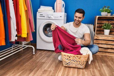 Çamaşır odasında kendine güvenen genç İspanyol adam gülümsüyor.