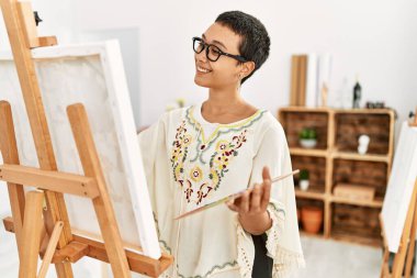 Genç İspanyol kadın resim stüdyosunda kendine güvenen gülümsüyor.