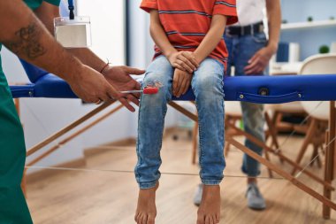 Family having medical consultation doing reflex knee test at clinic