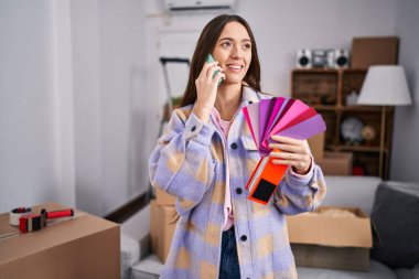 Genç, güzel, İspanyol bir kadın akıllı telefondan konuşuyor. Yeni evinde renk seçiyor.