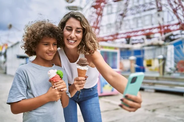 Mother and son eating ice cream make selfie by the smartphone at theme park