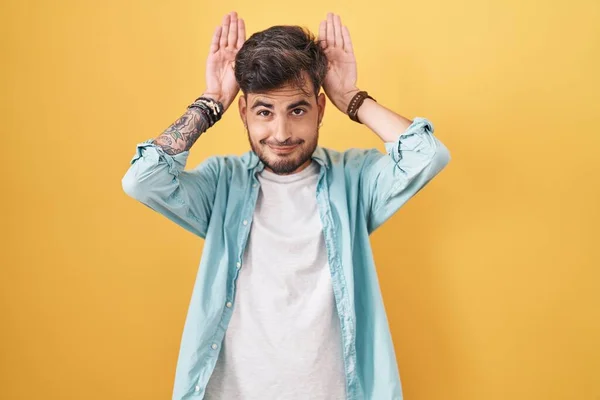 Молодий Іспаномовний Чоловік Татуюваннями Стоять Над Жовтим Тлом Робить Жест — стокове фото