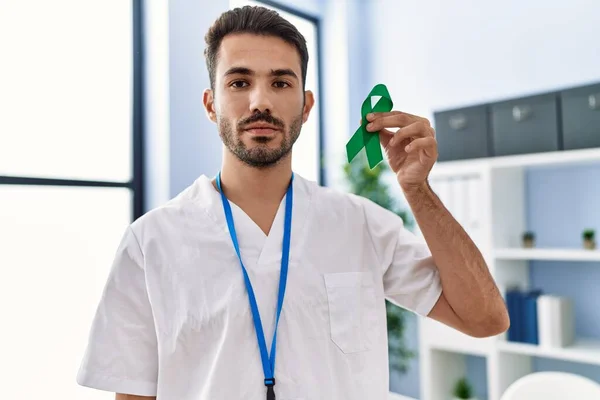 Young Hispanic Doctor Man Holding Support Green Ribbon Clinic Thinking — Stockfoto