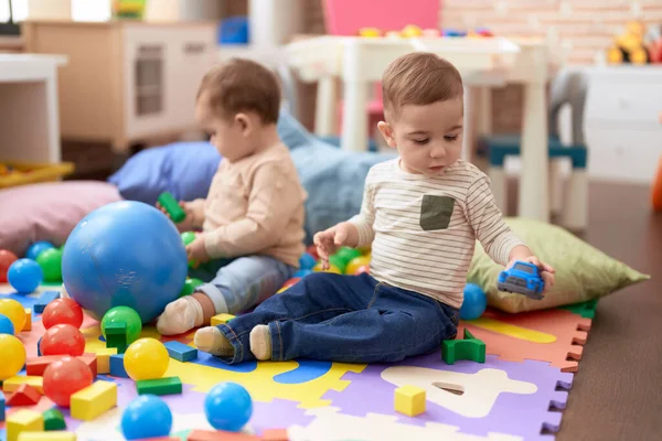 Anaokulunun Zemininde Oturan Iki Küçük Bebek Top Arabayla Oynuyorlar — Stok fotoğraf