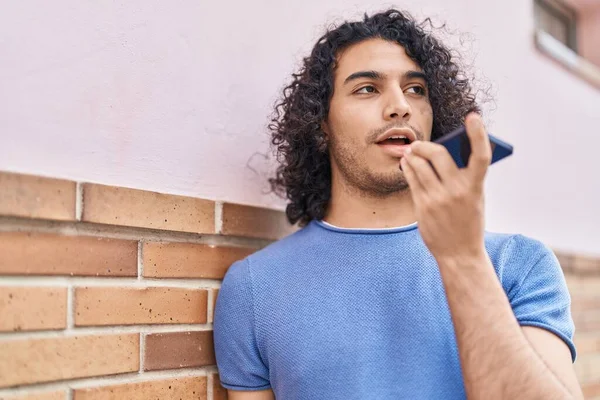 Young latin man talking on smartphone with serious expression at street