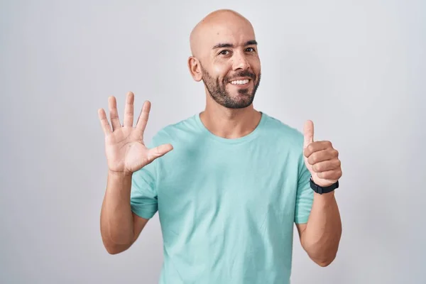 中年秃头男子站在白种人的背景上 用六号手指指指指点点 面带微笑 自信而快乐 — 图库照片