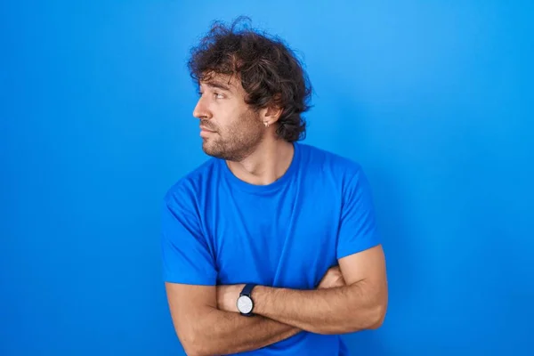 Hispanic Young Man Standing Blue Background Looking Side Arms Crossed — Stockfoto