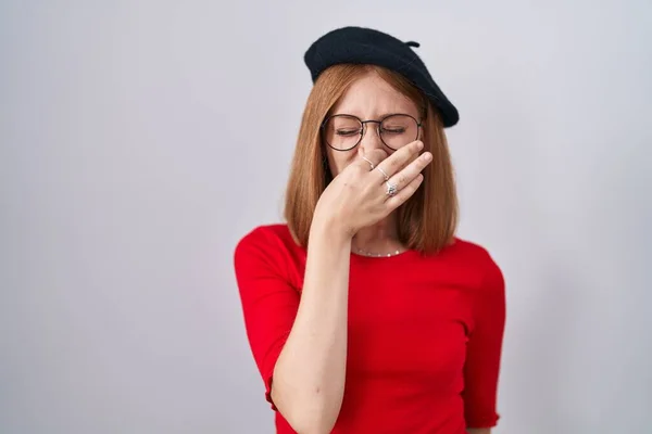 Young Redhead Woman Standing Wearing Glasses Beret Smelling Something Stinky — Stock fotografie