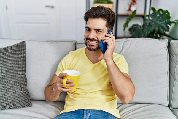 Young Hispanic Man Talking Smartphone Drinking Coffee Home — Fotografia de Stock