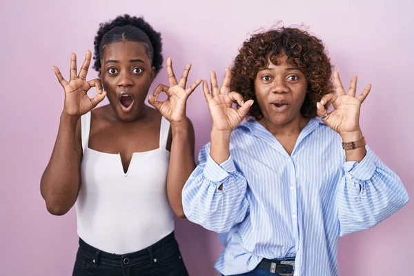 Two African Women Standing Pink Background Looking Surprised Shocked Doing — Stok fotoğraf
