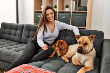 Kanepede oturmuş köpeklerle gülümseyen İspanyol bir kadın.