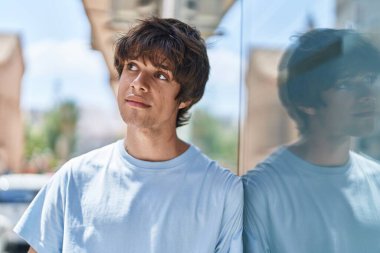 Sokakta ciddi bir ifadeyle yan tarafa bakan genç sarışın adam.