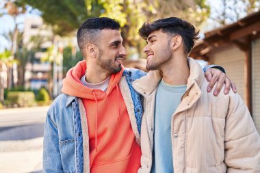 İki erkek parkta birbirlerine sarılıyorlar.