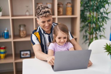 Baba-kız, baba-kız evdeki masada dizüstü bilgisayar kullanıyor.