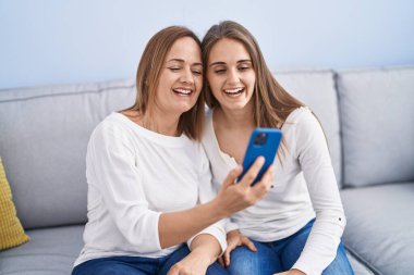 Evde akıllı telefon kullanan iki kadın anne ve kız.