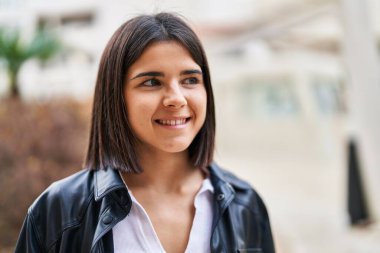 Young beautiful hispanic woman smiling confident looking to the side at street
